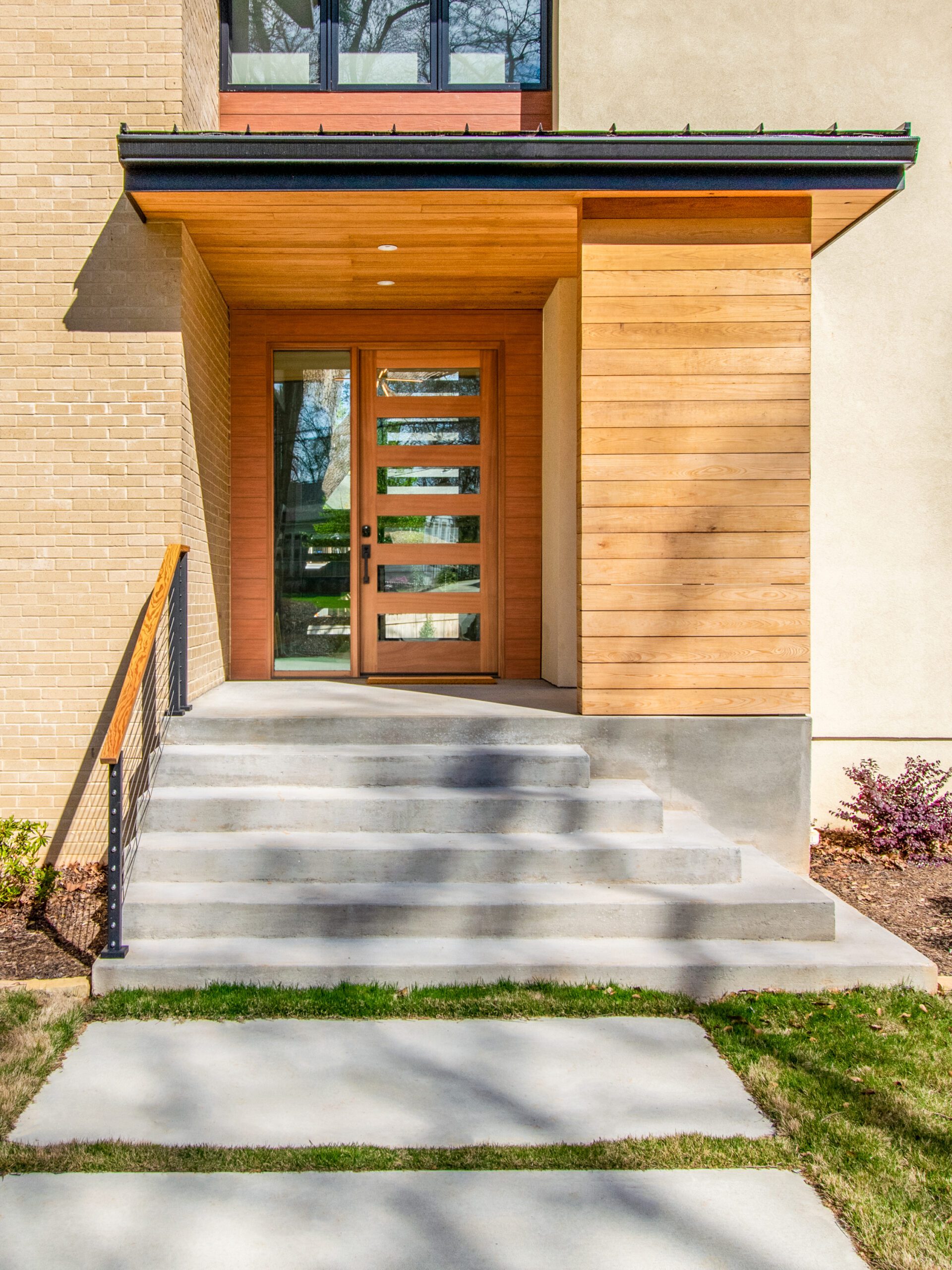 Cascading concrete stairs leading to modern wood front door