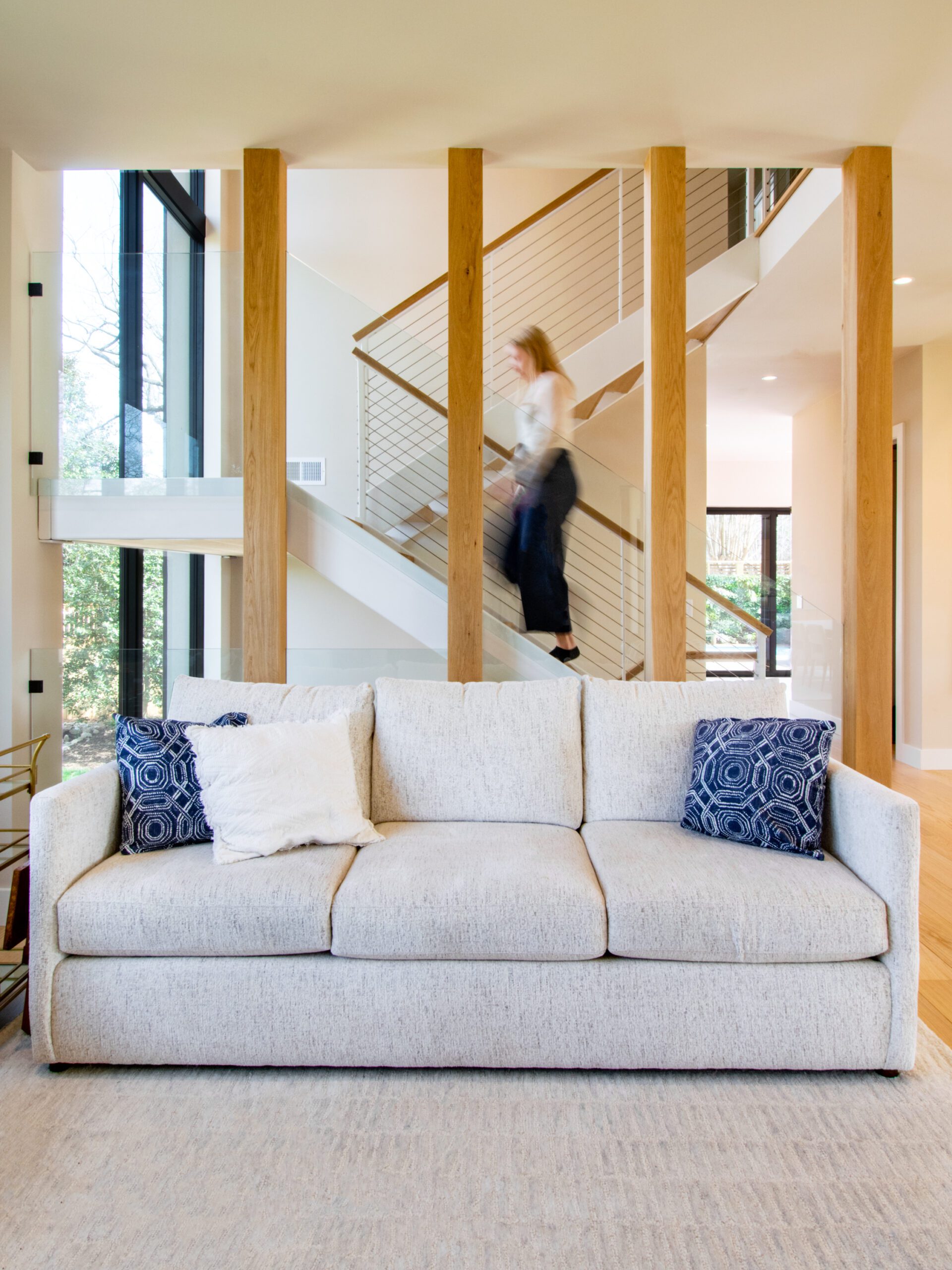 Person walking up modern stairs. White oak wrapped columns