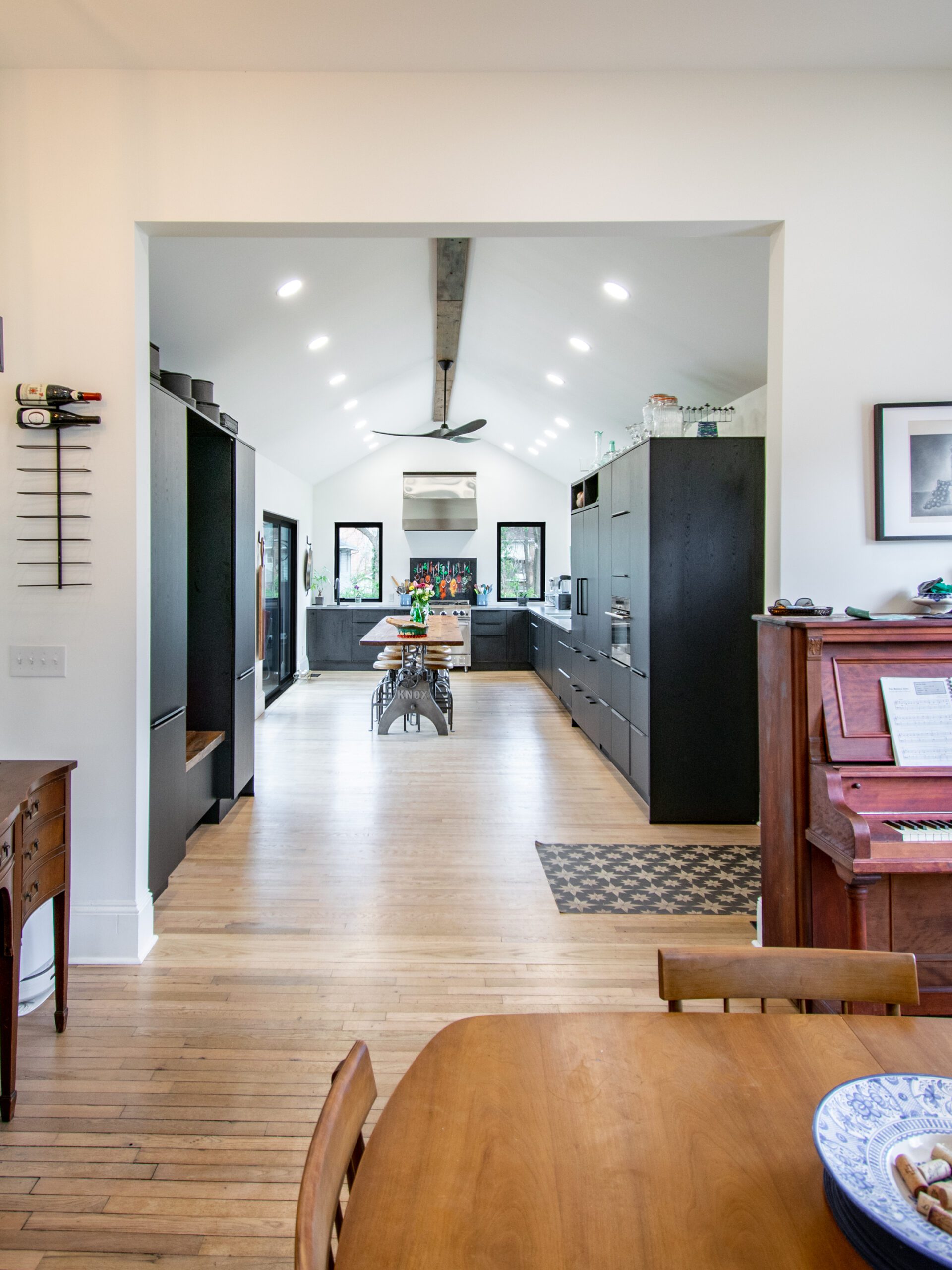 View of kitchen with vaulted ceiling and modern cabinetry from dining room in renovated Victorian house