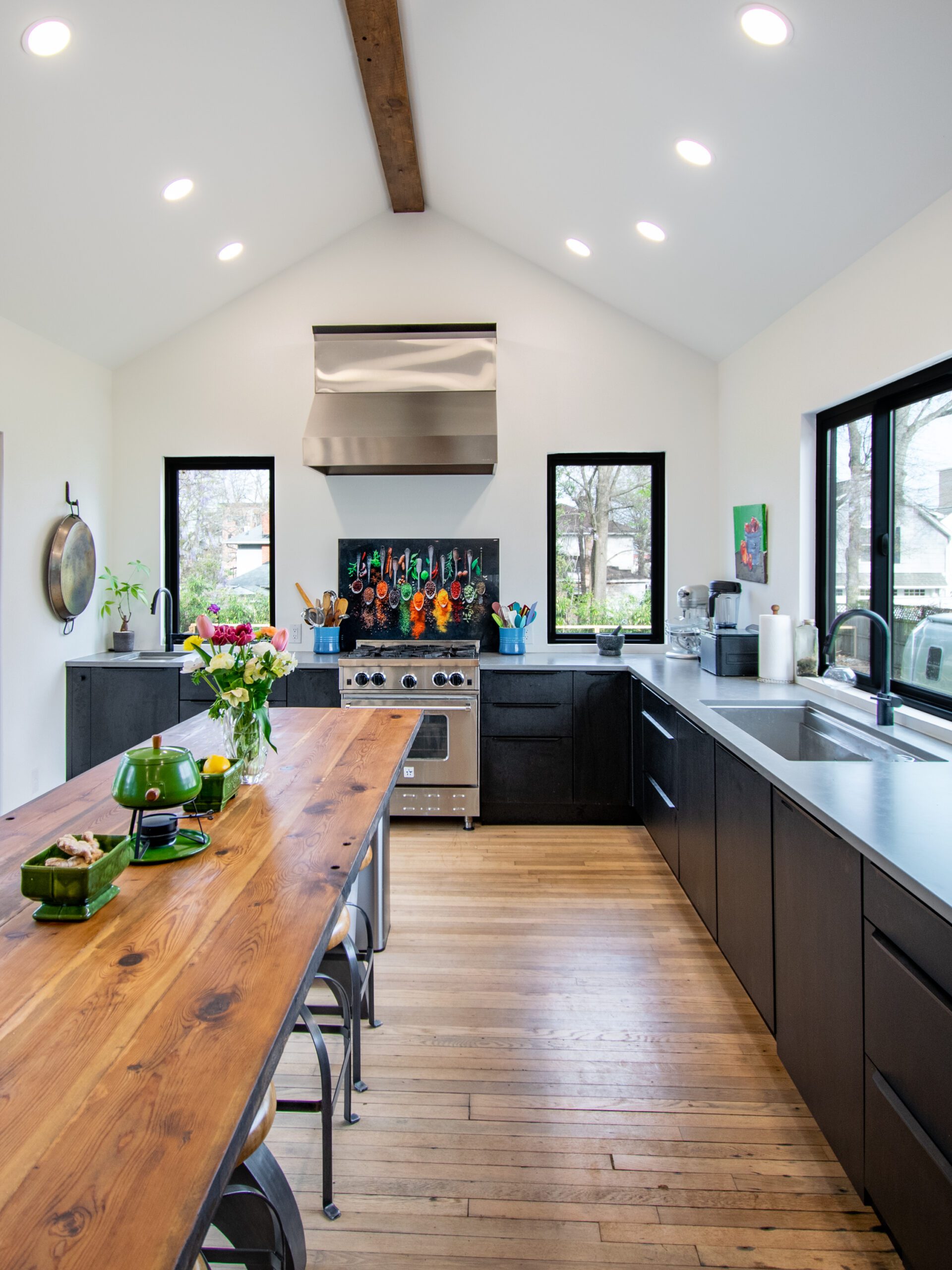 Modern black kitchen cabinets with stainless steel countertop and wood island