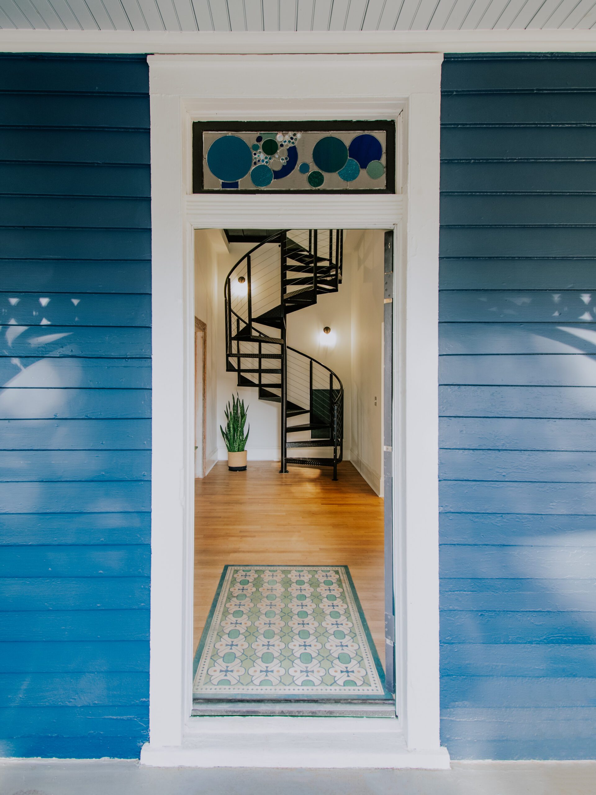 Renovated Victorian house with open front door showing view of spiral staircase